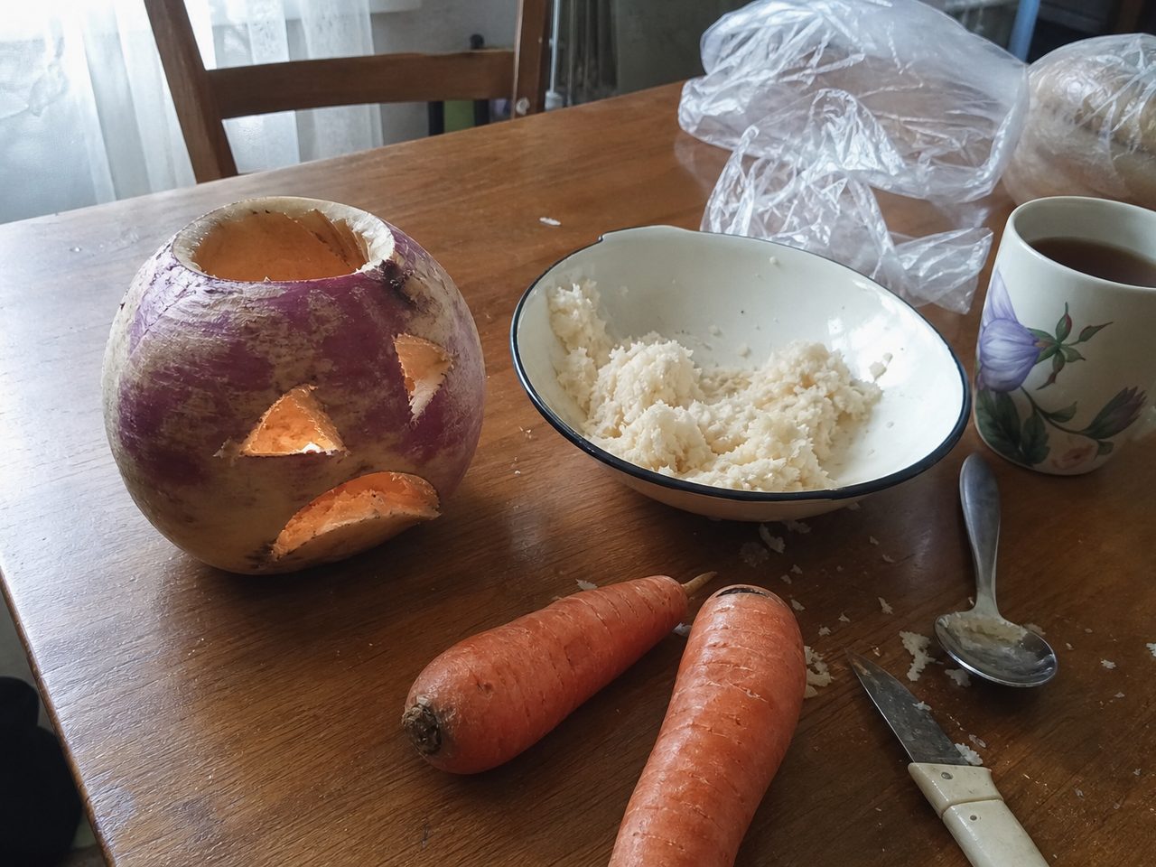 Вырезанный фонарь из репы, миска с мякотью и морковь на кухонном столе