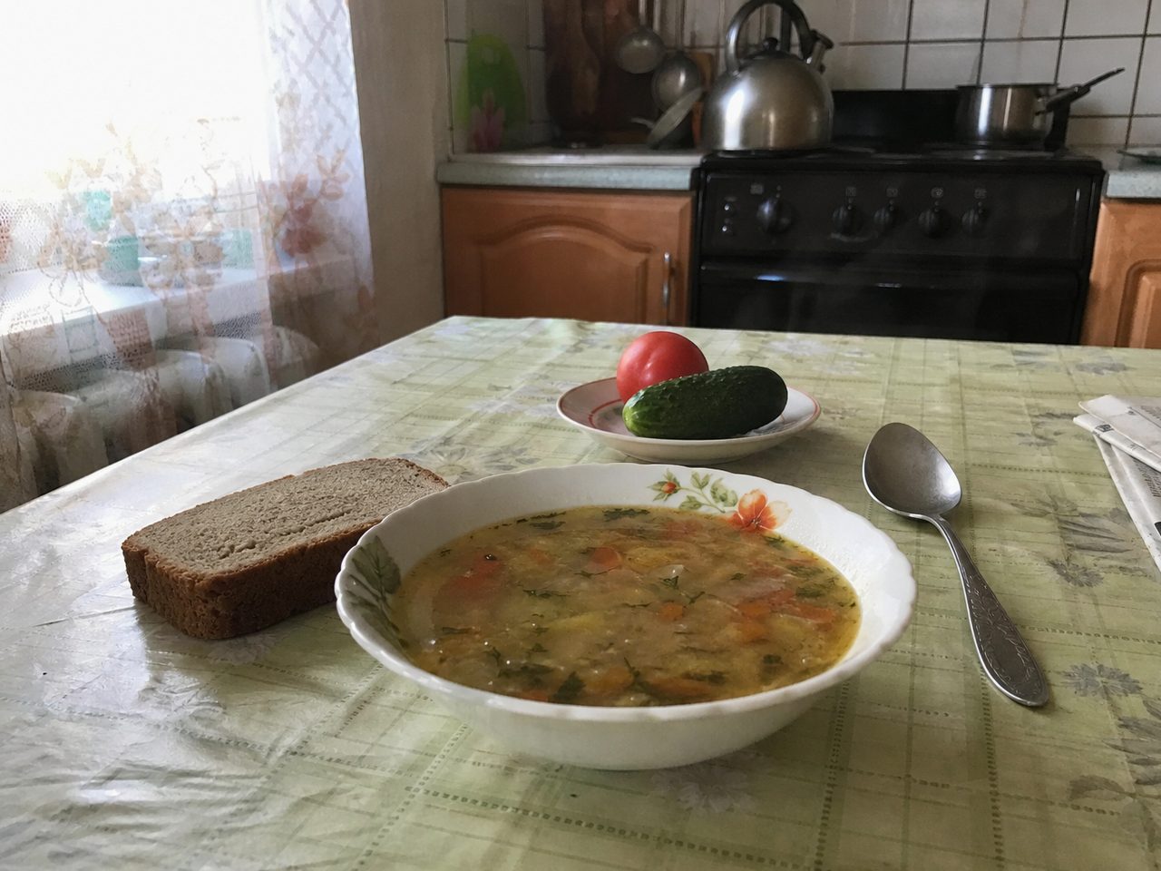 Тарелка супа, хлеб и овощи на кухонном столе